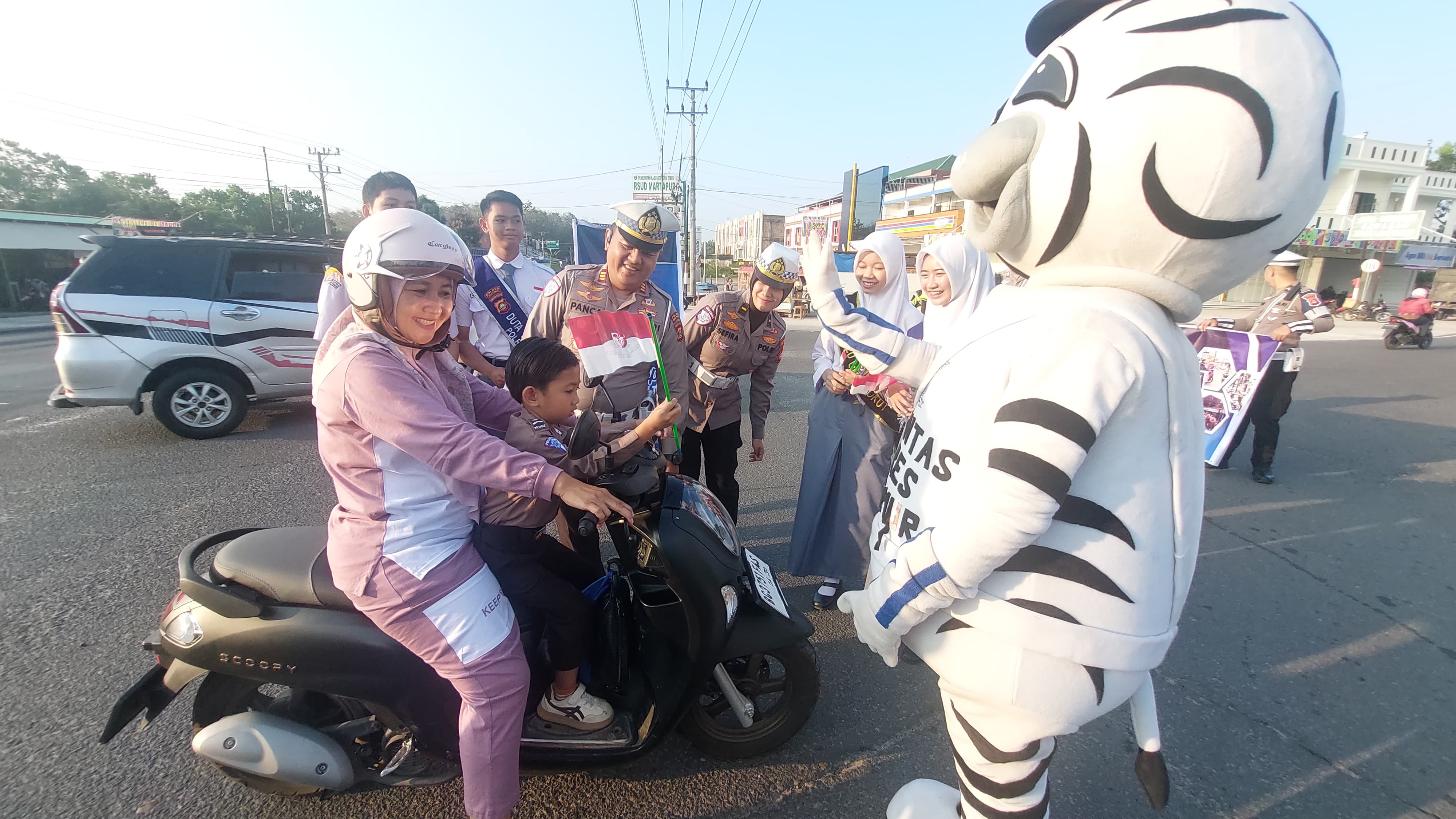 Satlantas Polres OKU Timur Menyapa Warga, Hadirkan Badut Zebra Bagikan Bendera